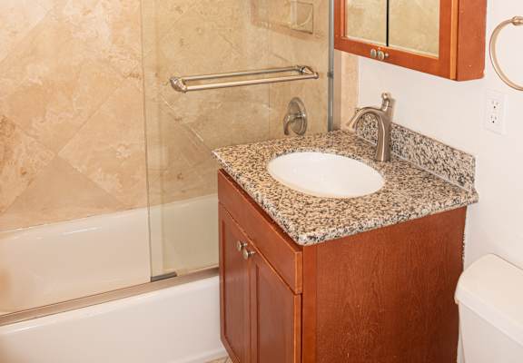 A bathroom with a sink, mirror, and shower.