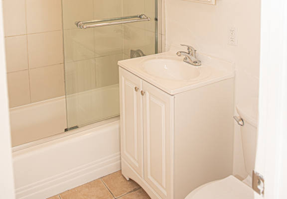 A white bathroom with a glass shower door and a white sink.