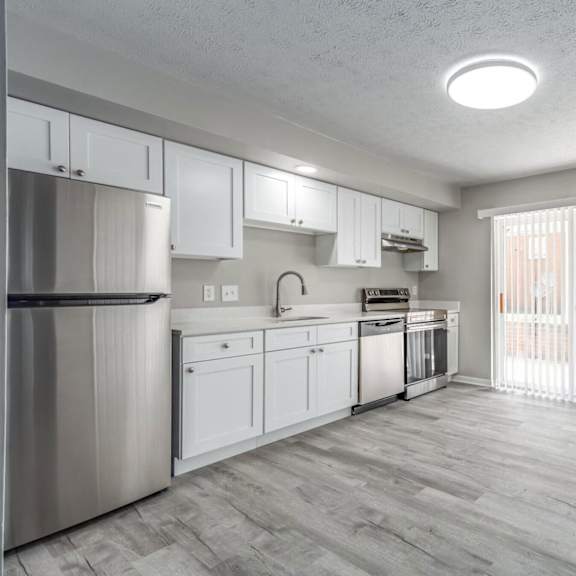 A kitchen with white cabinets and a stainless steel refrigerator.
