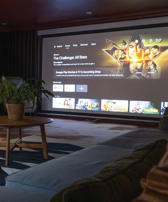 A living room with a large screen displaying a movie.