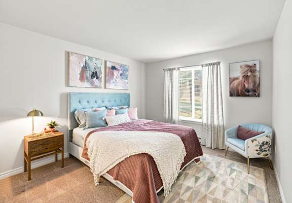 A bedroom with a large bed and a chair.