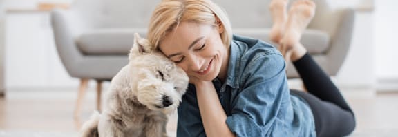 A woman is lying on the floor with her dog.