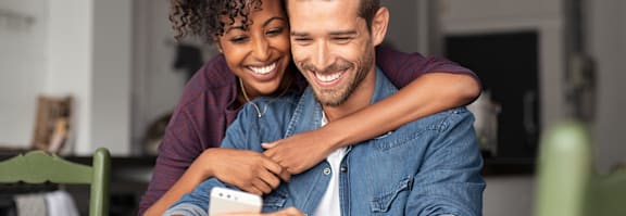 A man and woman are sitting closely together, with the man's arm around the woman's shoulder.
