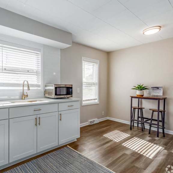 A kitchen with white cabinets and a microwave on the counter.