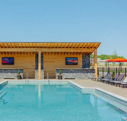 the pool and spa area of a resort style swimming pool with a wood pavilion