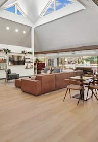 a large living room with a high ceiling and a dining room with tables and chairs