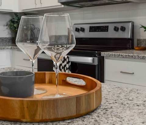 A modern kitchen with a wooden cutting board and two glasses on it.