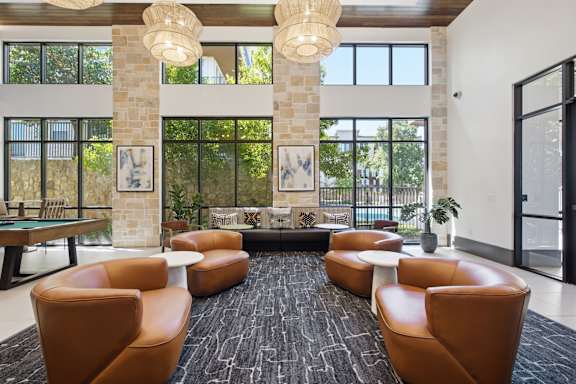 A large room with a pool table and leather chairs.