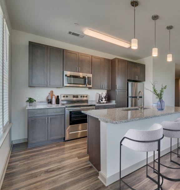 an open kitchen and dining room with an island and stools  at Vue at Westchester Commons, Midlothian, VA, 23113