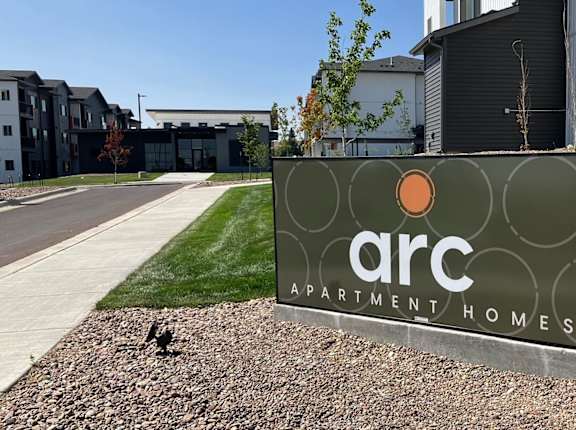 A sign for ARC Apartment Homes in front of a building.