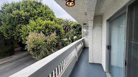 A balcony with a white railing and a glass door.