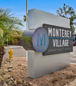 a sign for monterey village with a yellow fire hydrant in the background