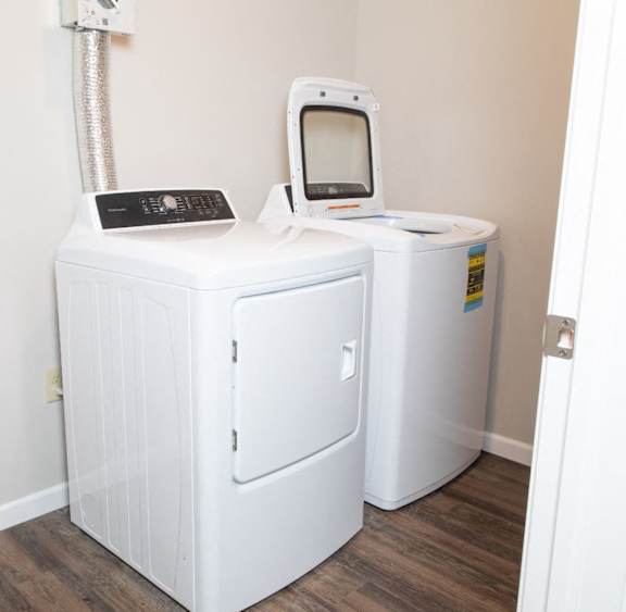 A white medical device with a monitor sits on a wooden floor.