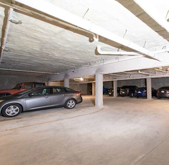 A parking garage with a silver car in the foreground.