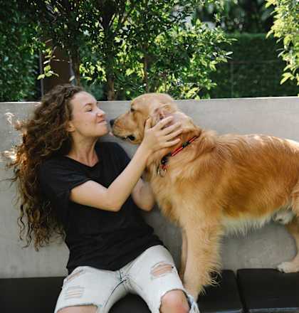 a woman sitting on a bench kissing a dog