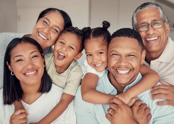 A family of five is smiling and hugging together.