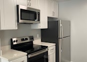 Thumbnail 6 of 9 - a kitchen with white counters and stoves and a wooden wall