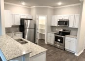 Thumbnail 7 of 60 - B1 (1-car) Kitchen with pantry with built-in shelving, granite countertops, stainless steel appliances