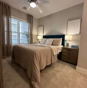 A bedroom with a bed, dresser, and a ceiling fan.