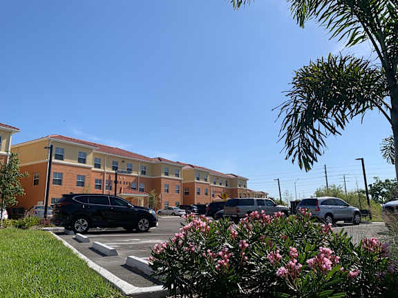 A black car is parked in a parking lot in front of a building.