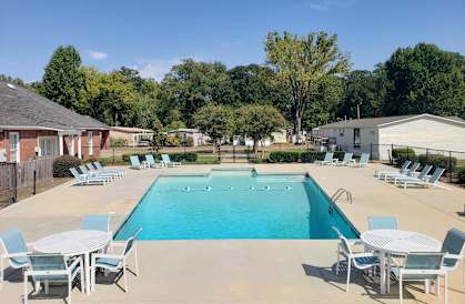 A large swimming pool surrounded by chairs and tables.