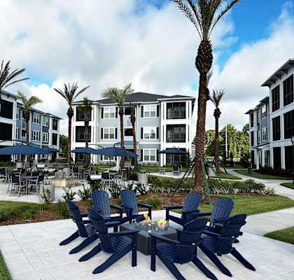 a patio area with blue chairs and tables and umbrellas in front of apartments