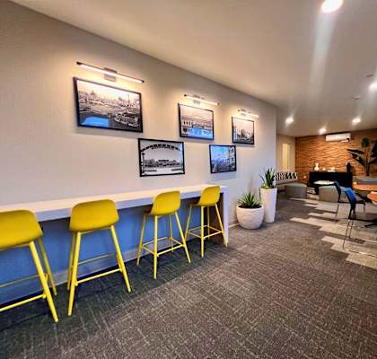 a lounge area with yellow chairs and tables and a piano