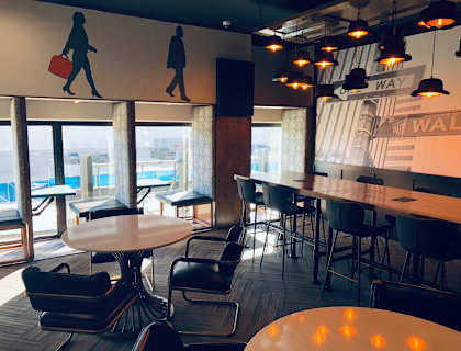 A modern cafe with tables and chairs and a mural of a man carrying a suitcase at Park Michigan Apartments, Chicago, 60605