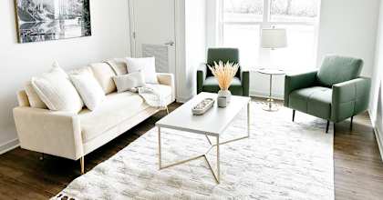 A white couch with a white coffee table in front of a white wall with a black and white picture hanging on it.
