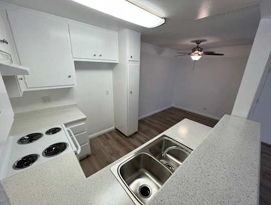 a kitchen and living room with a sink and a ceiling fan