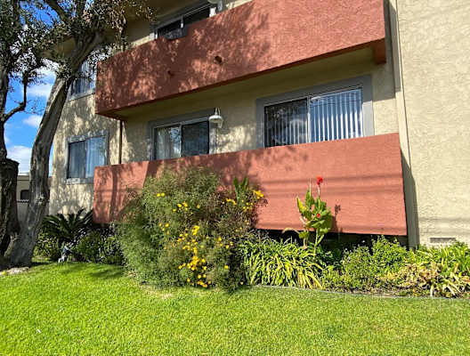A building with a red awning and a green lawn in front.