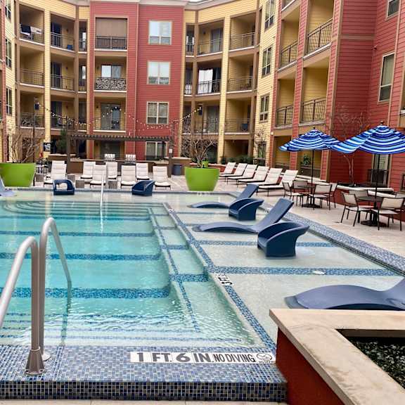 A swimming pool at Florence on the Harbor surrounded by pool chairs and umbrellas.