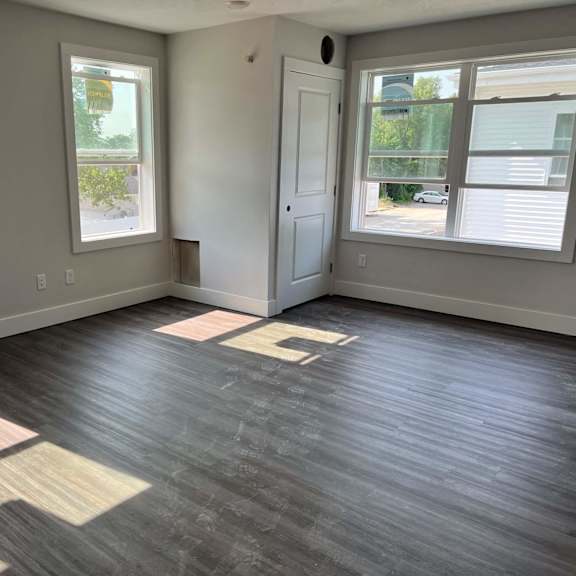 A room with a ceiling fan and a window overlooking a construction site. at Michigan Street Apartment Homes, Michigan