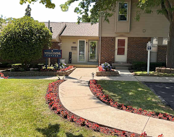 a sidewalk in front of a building with flowers and plants