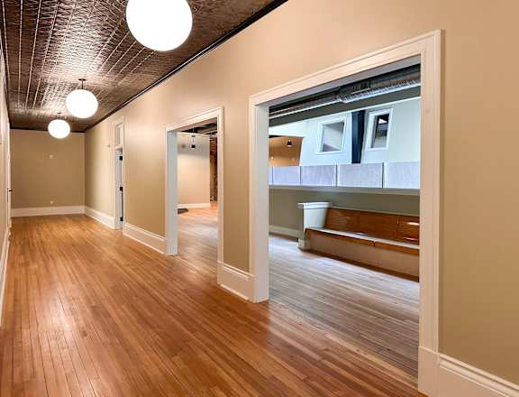 A hallway with wood floors and a bench.