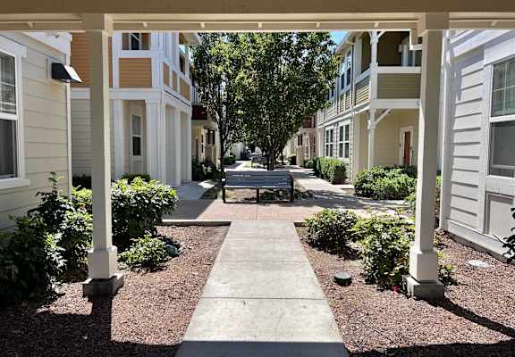 A walkway leads between two rows of white and beige houses.