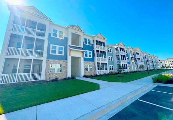 A row of modern apartment buildings with balconies and a clear blue sky above.