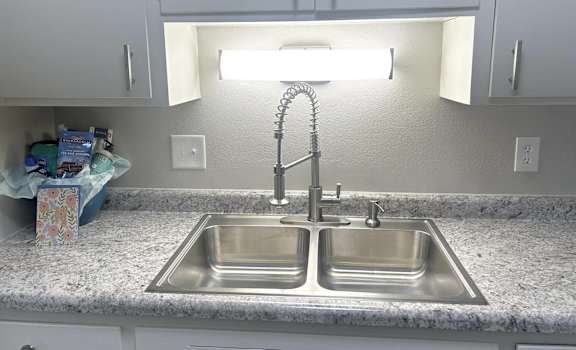 a stainless steel sink in a kitchen with white cabinets
