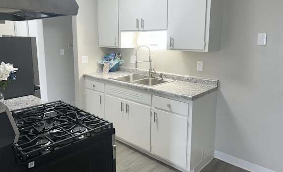 a kitchen with white cabinets and a stove and a sink