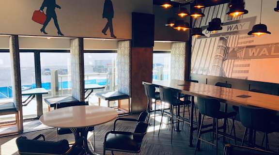 A modern cafe with tables and chairs and a mural of a man carrying a suitcase at Park Michigan Apartments, Chicago, 60605