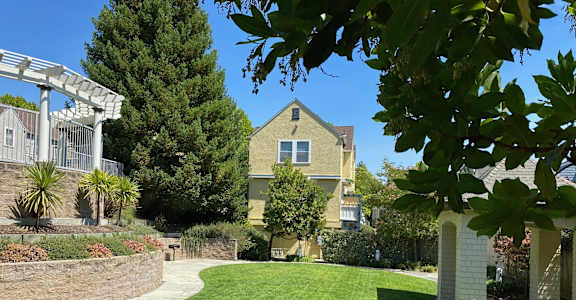 A house with a well-kept lawn and a white pergola. at Westmont Place Townhomes Apartments, Santa Cruz, California
