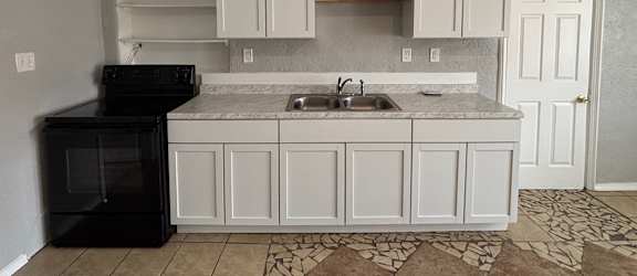 A kitchen with white cabinets and a black oven.
