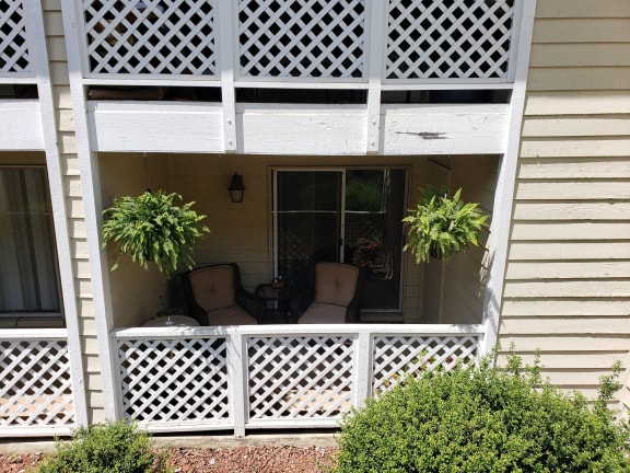 the front porch of a house with chairs and a porch swing