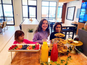 a group of children sitting at a table with food