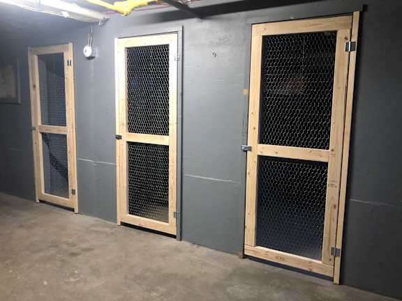 Three wooden doors with mesh windows are in a room.