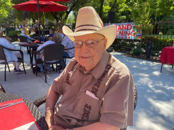 an older woman wearing a straw hat sitting at a table