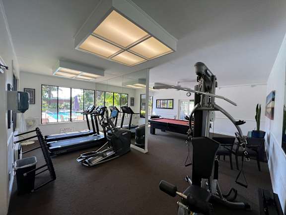 a gym with exercise equipment and windows with a pool