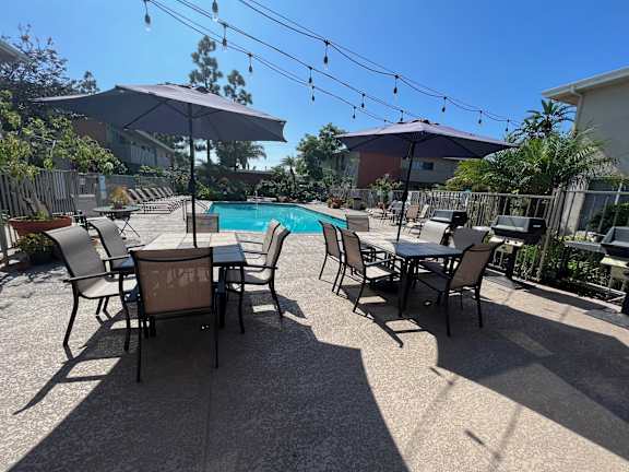 a patio with tables and umbrellas and a swimming pool