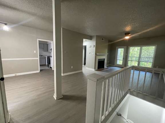A spacious room with a white railing and wooden flooring.