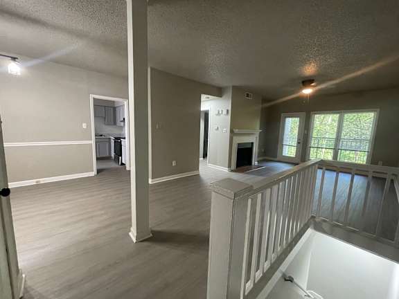 A room with a white railing and wooden floors.